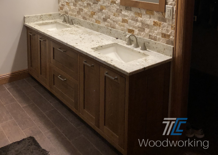 brown bathroom vanity, tiled back splash, light colored countertop 