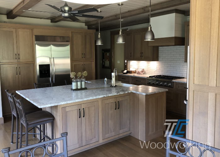 light brown kitchen island, overhead ceiling fan and lights, stainless steel refrigerators 