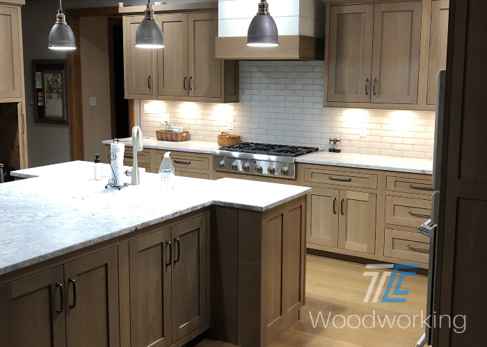 wooden kitchen cabinets, stainless range, overhead metal lights, granite counters