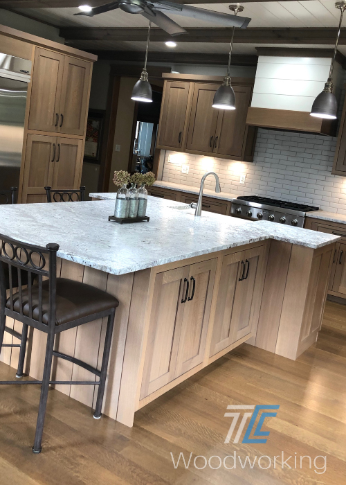 light brown kitchen cabinets, kitchen island, pendant lights, tiled back splash